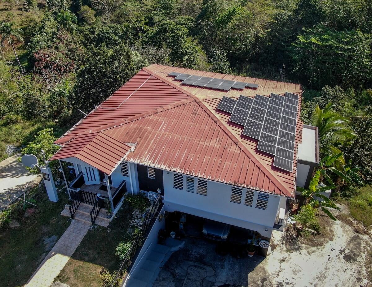 Vista aérea de una casa puertorriqueña con techo de zinc y paneles solares